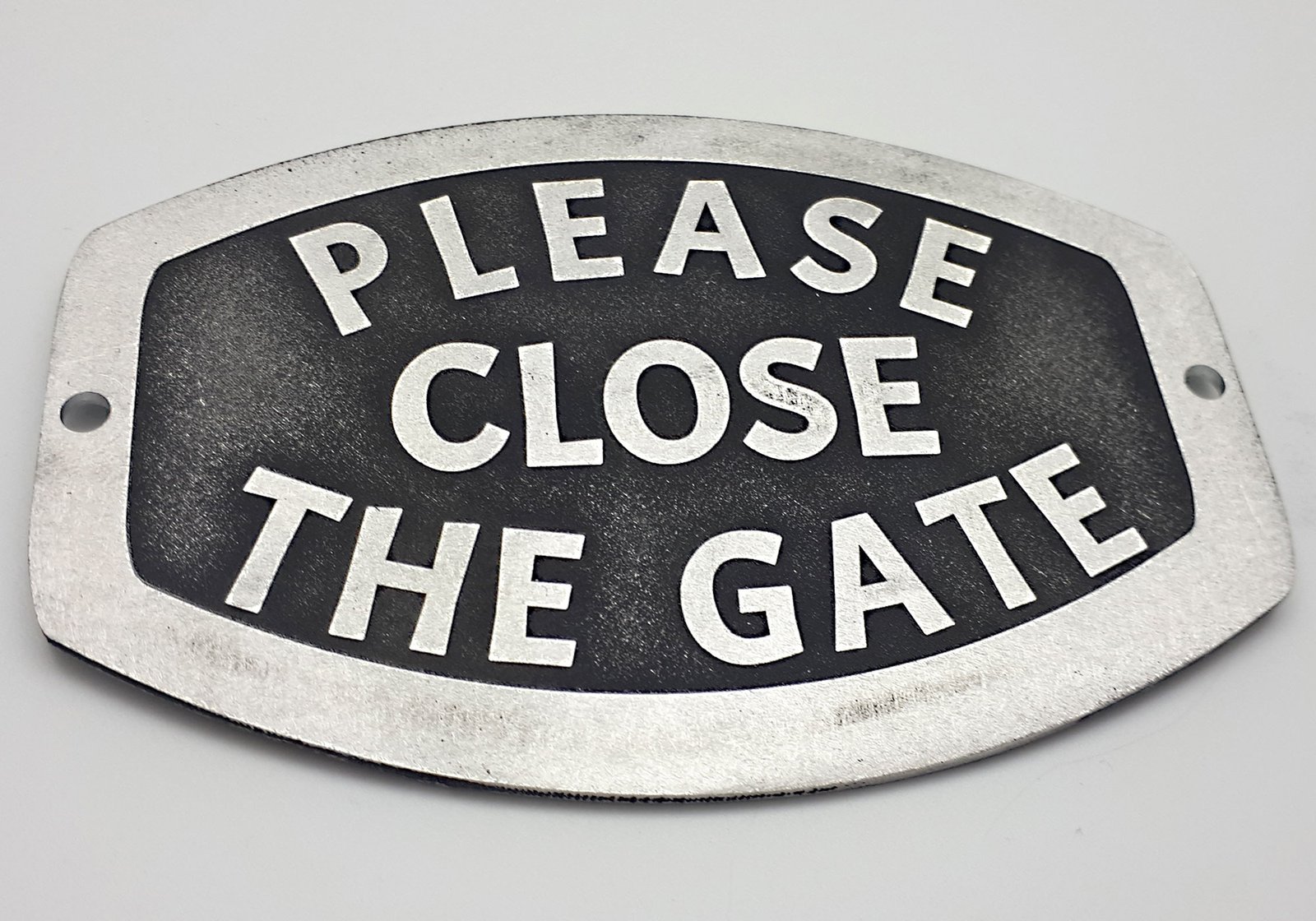 A solid aluminium gate sign reading "Please flos the gate' designed to last and remain clear. Silver coloured text against black background to stand out.