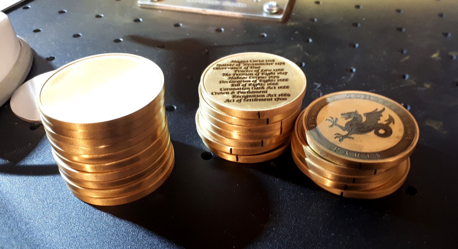 stack of brass coins being engraved on a laser machine