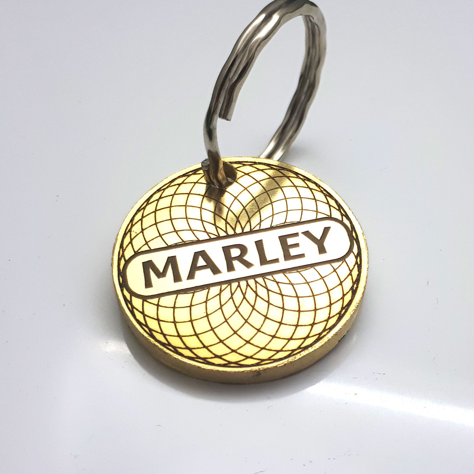 High quality, thick, solid brass pet ID tag, 3mm thickness. Engraved deeply with a repeating circular pattern in a guilloche style, along with a pet name.